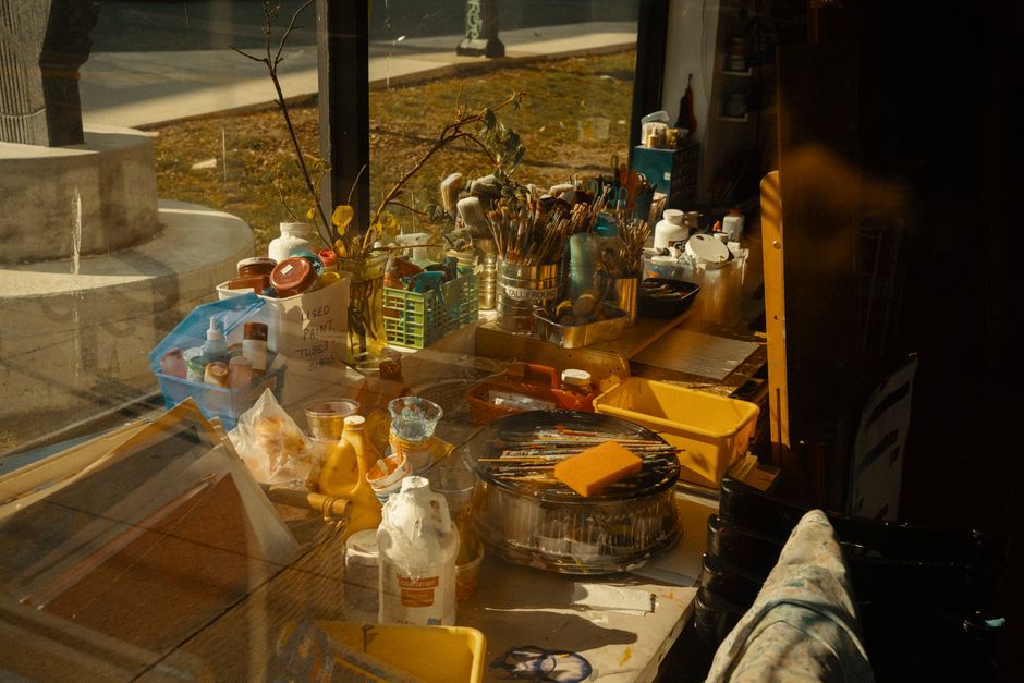 A well-lit art studio with brushes, paints, and tools bathed in warm sunlight, creating a creative atmosphere.